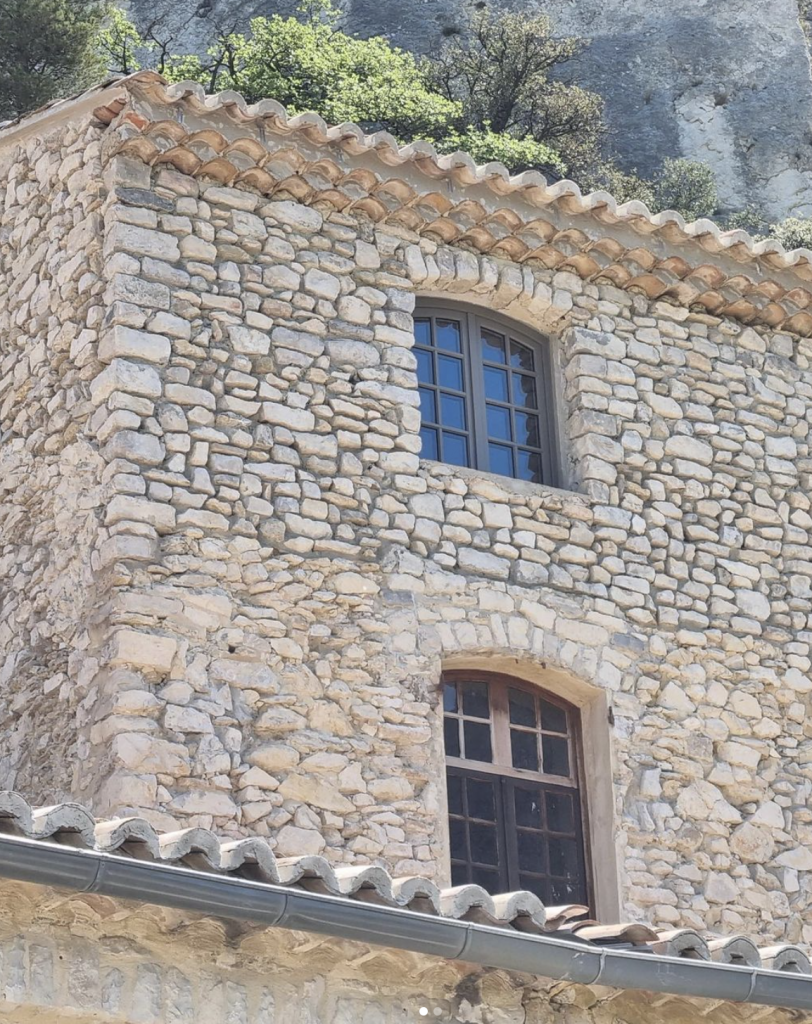 façade maison en pierre avec fenêtre marron petit carreaux 